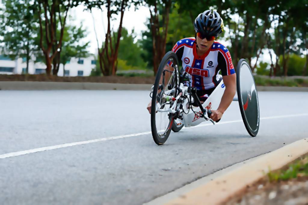 Photo of Oksana competing in para-cycling in her Team USA jersey.